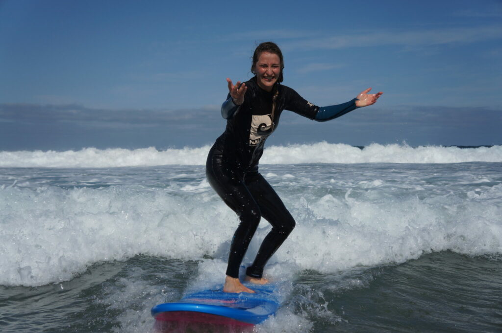 Frau surft Welle und lacht