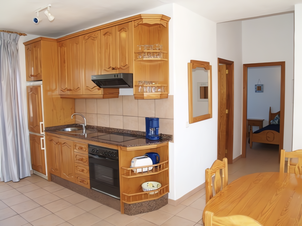 Küche mit Holzschränken, Herd, Kühlschrank und Esstisch in einem Raum.
