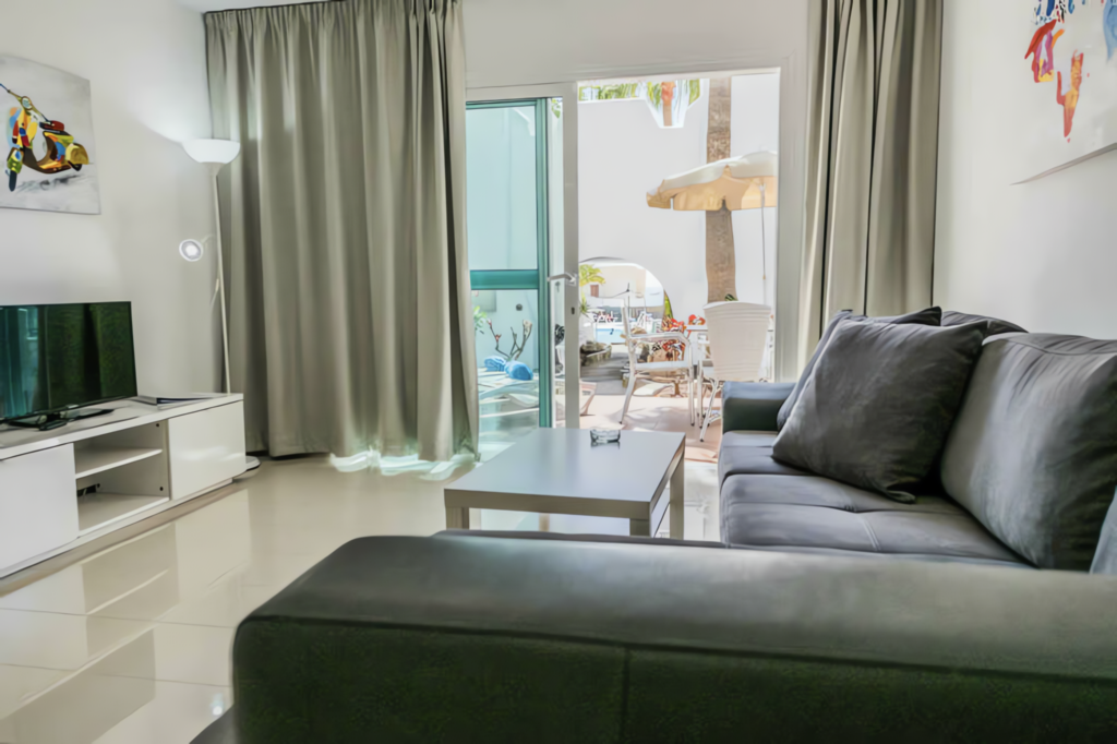 Ein modernes Wohnzimmer mit einem grauen Sofa und einem Fernseher auf einem weißen TV-Ständer.