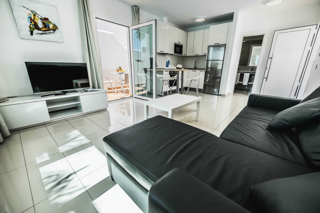Schwarzes Sofa in einem modernen Wohnzimmer mit offener Küche und großen Fenstern.