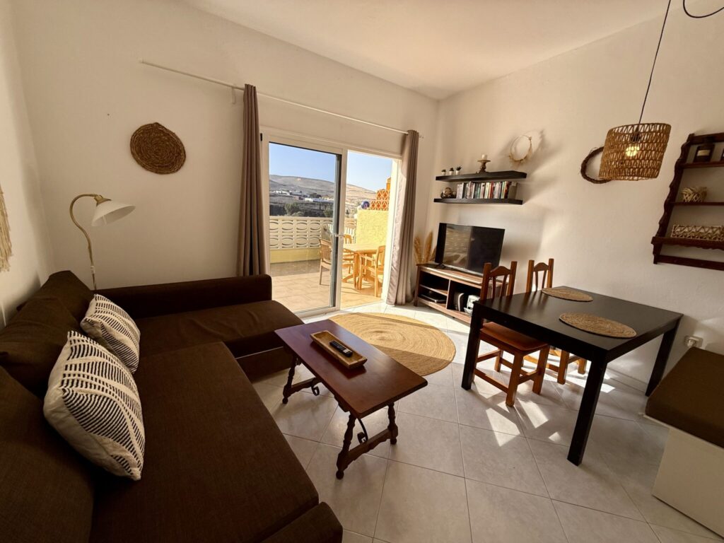 Gemütliches Wohnzimmer im Surfcamp-Apartment mit Sofa, Tisch und Fernseher.