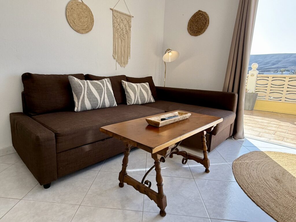 Braunes Sofa mit Kissen und Holztisch in einem Wohnzimmer mit neutralen Farben.