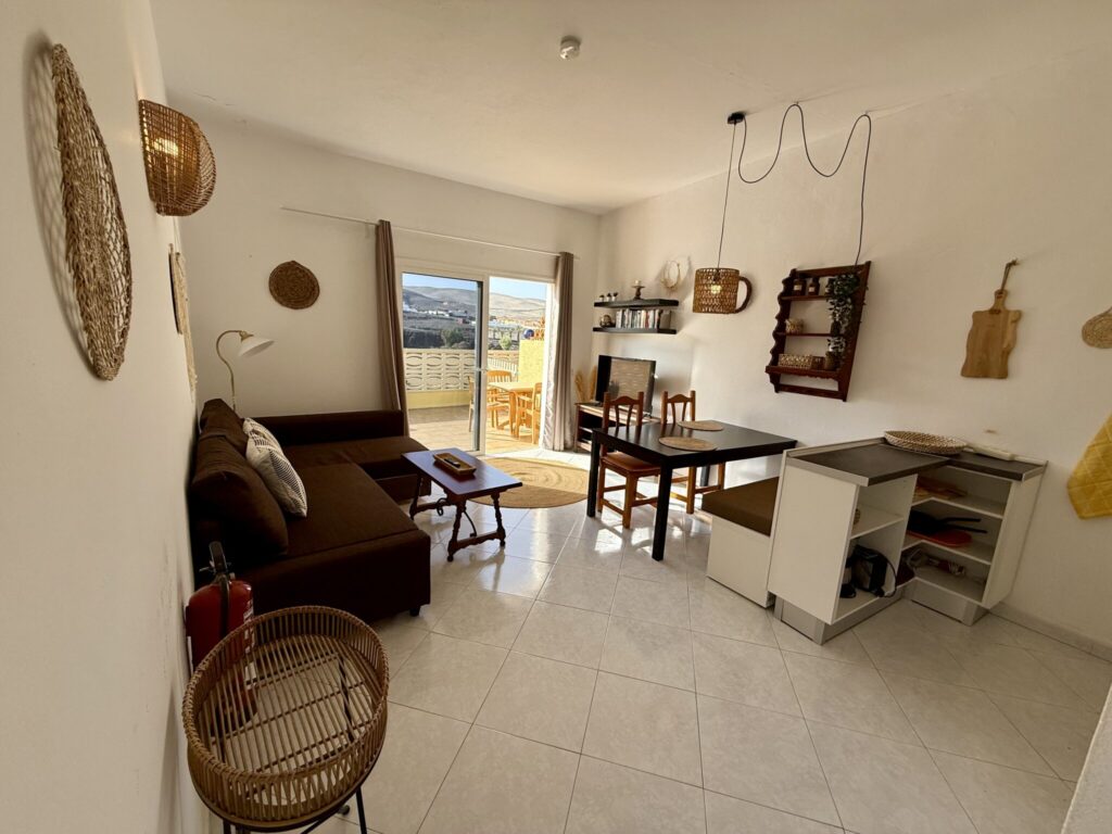 Helles Wohnzimmer mit einem Sofa, Esstisch und verschiedenen Wanddekorationen.