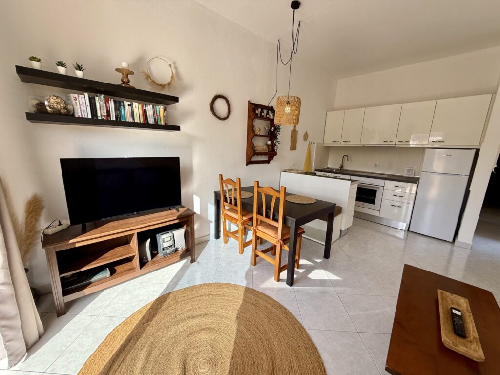 Küche und Wohnbereich eines Apartments mit Fernseher, Tisch und Stühlen in Fuerteventura.