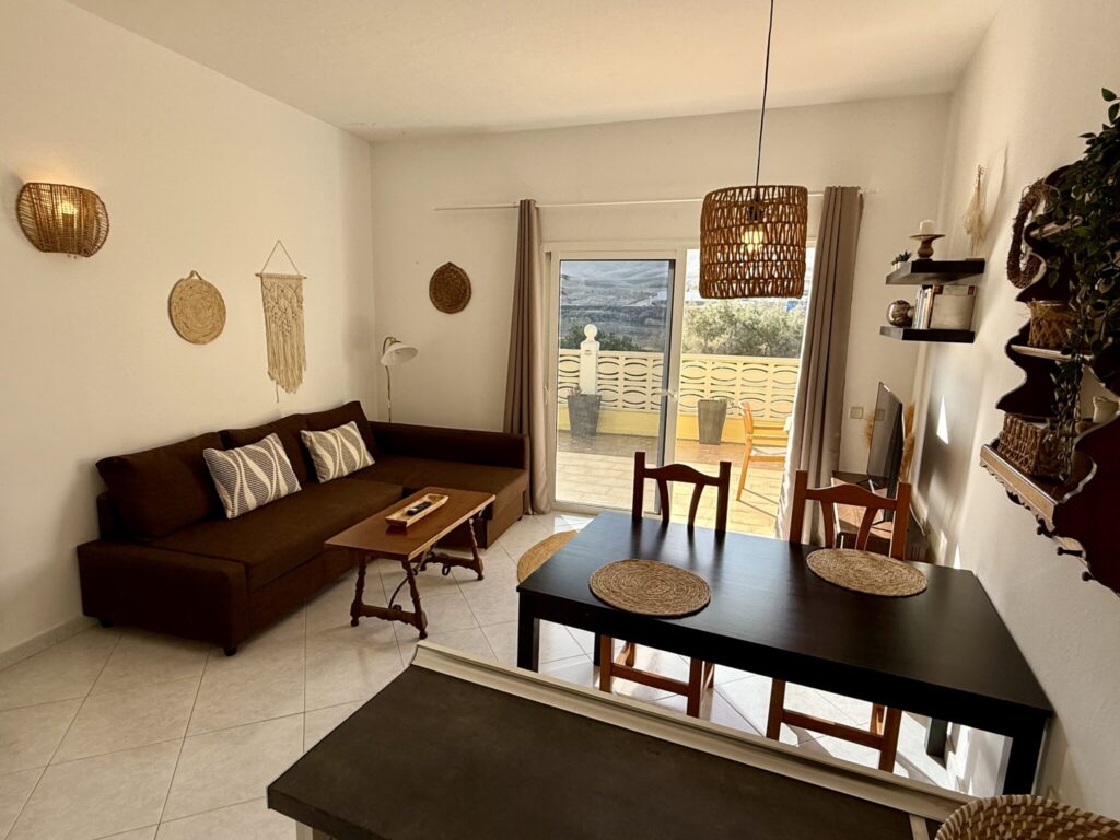 Ein Wohnzimmer mit einem braunen Sofa, einem Esstisch und dekorativen Elementen an der Wand.