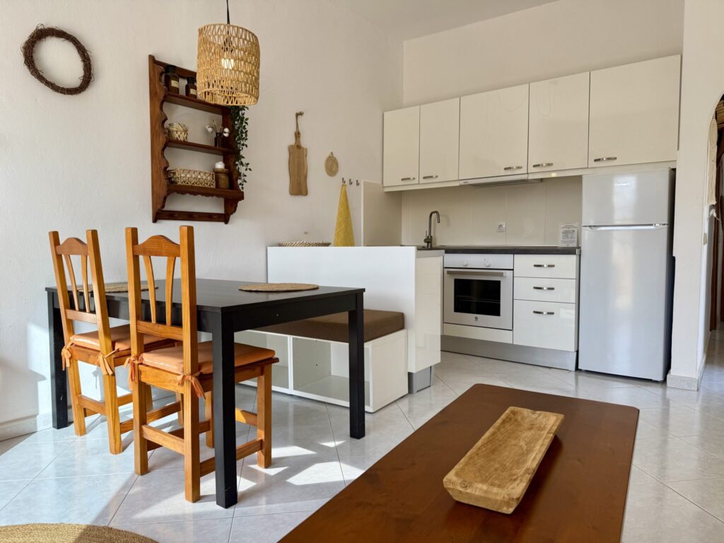 Küche und Essbereich in einem Apartment Küche mit weißen Schränken, Herd, Kühlschrank und einem Essbereich mit Holztisch und Stühlen.