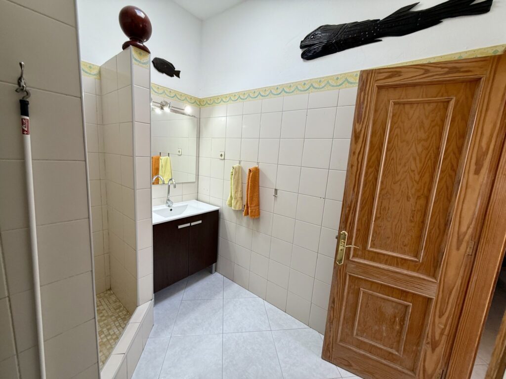 Badezimmer mit einem Waschbecken, Holzschrank und Handtüchern in orange und gelb.