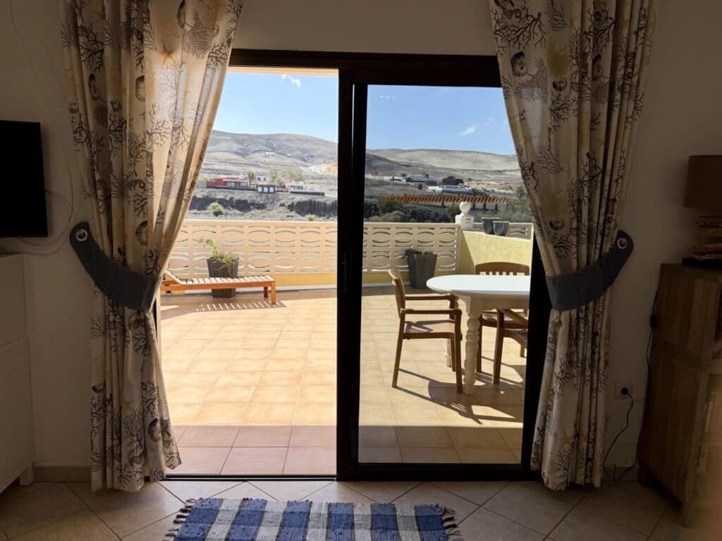 Terrasse mit einem Tisch und Stühlen, Blick durch eine Glastür in einem Apartment.