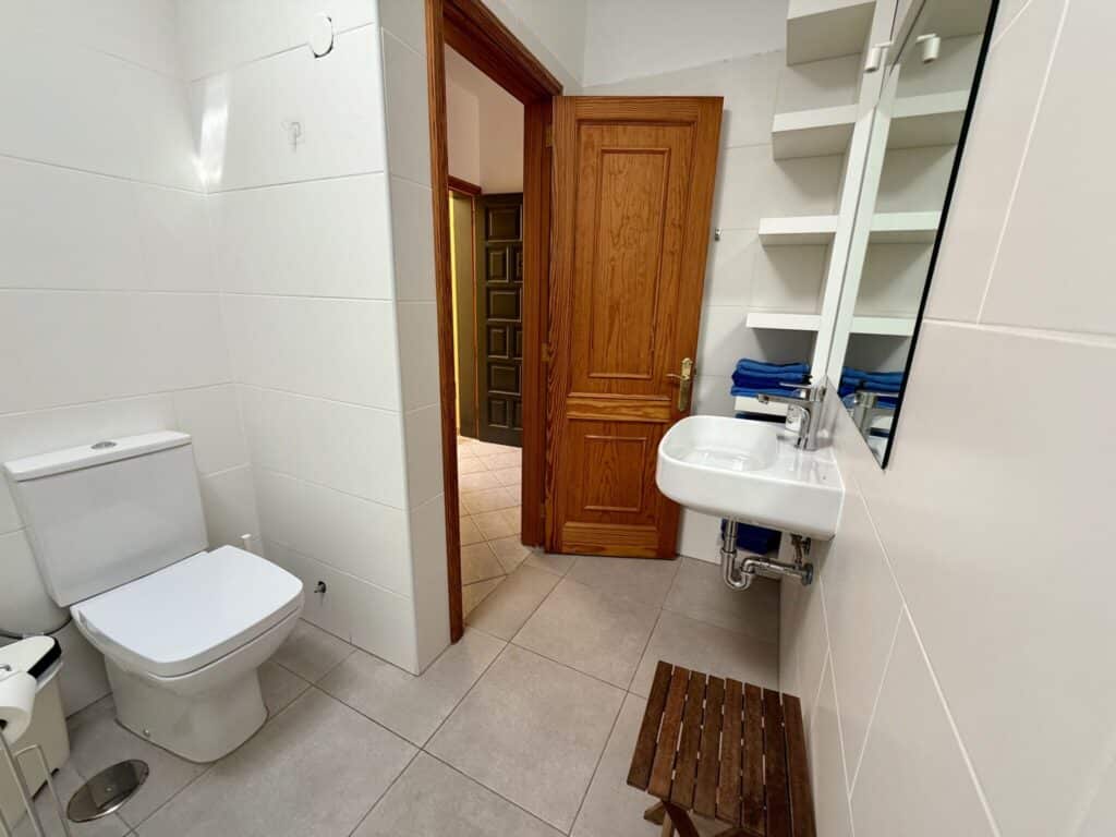 Ein Badezimmer mit einer Toilette, einem Waschbecken und einem Holzstuhl.