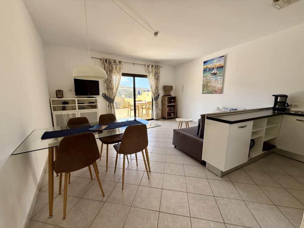 Ein Wohnzimmer mit einem Esstisch, Stühlen und einer Küchenzeile in einem modernen Apartment.