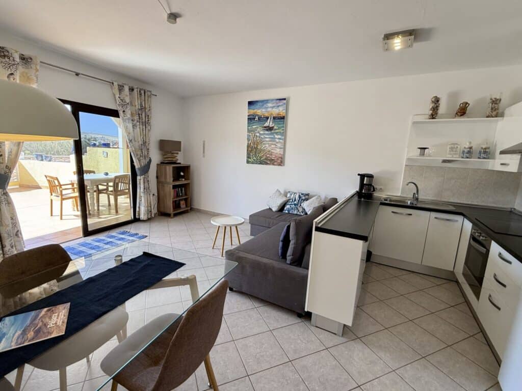 Innenansicht eines Apartments mit Wohnzimmer und offener Küche, inklusive Möbel und Dekoration.