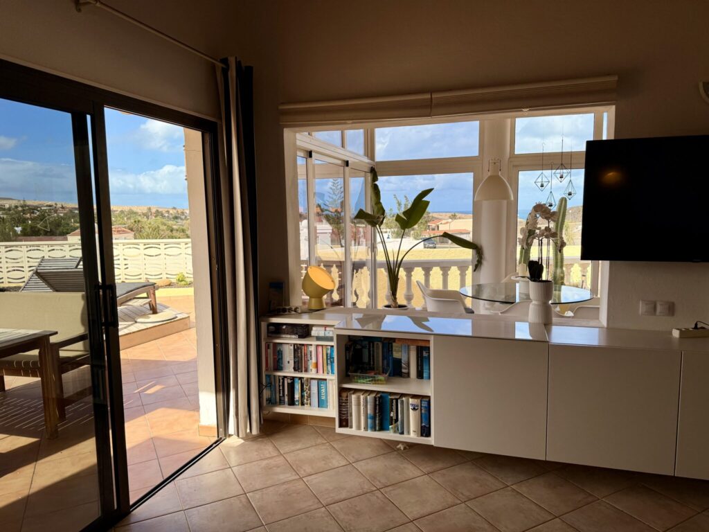 Innenansicht eines Apartments mit Fenster und Bücherregal Innenansicht eines Apartments mit einem Bücherregal und einem großen Fenster zur Terrasse.