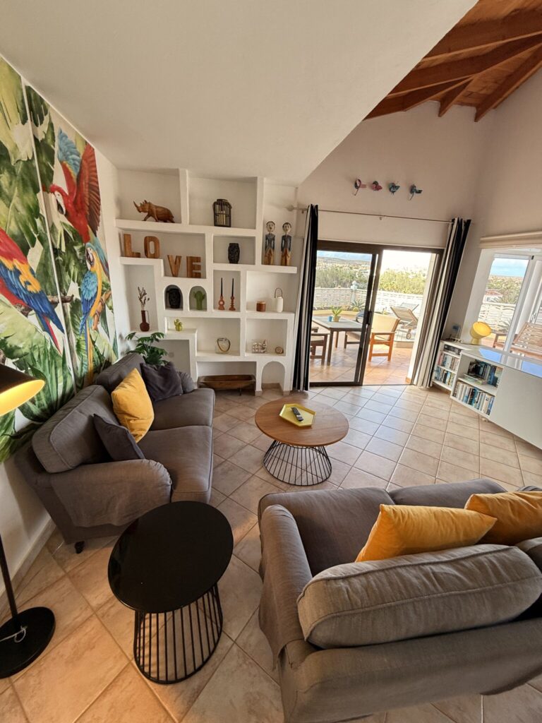 Wohnzimmer mit Sofas und Dekoration Wohnzimmer mit zwei grauen Sofas, einem Couchtisch und einer Wanddekoration mit Vögeln.