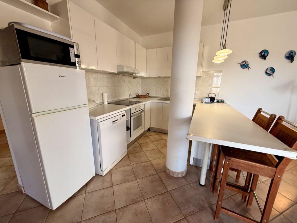 Küche in einem Apartment mit modernen Geräten Moderne Küche mit Kühlschrank, Geschirrspüler, Herd und Esstisch in einem Apartment.