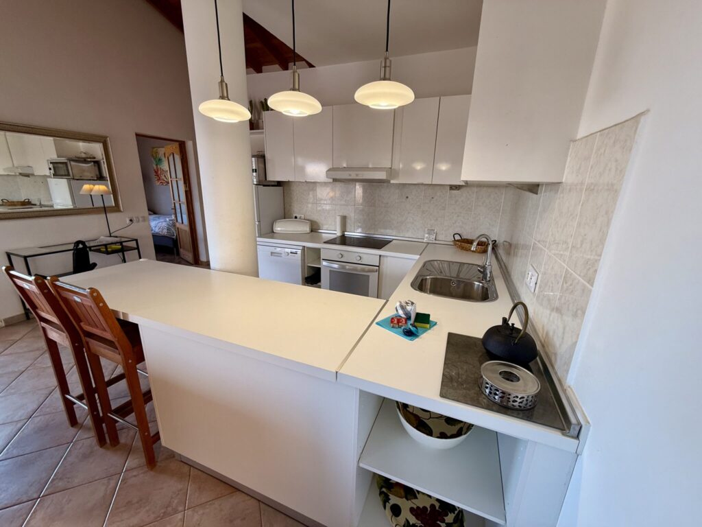Küche in einem Apartment auf Fuerteventura Moderne Küche in einem Apartment mit weißen Schränken, Spüle und Barhockern.