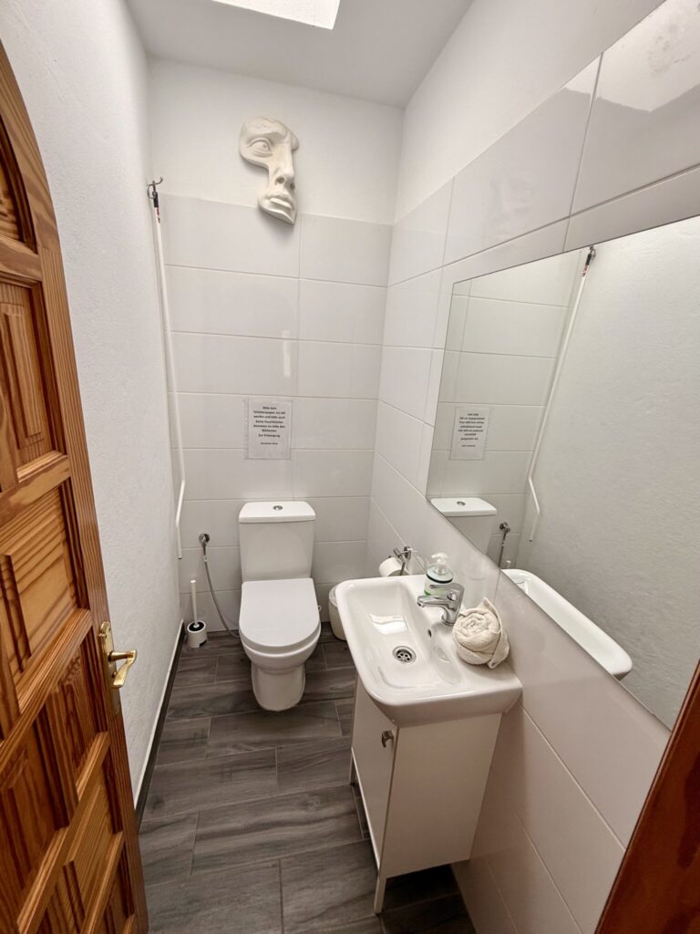 Badezimmer mit Toilette und Waschbecken Kleines Badezimmer mit Toilette, Waschbecken und Spiegel an der Wand.