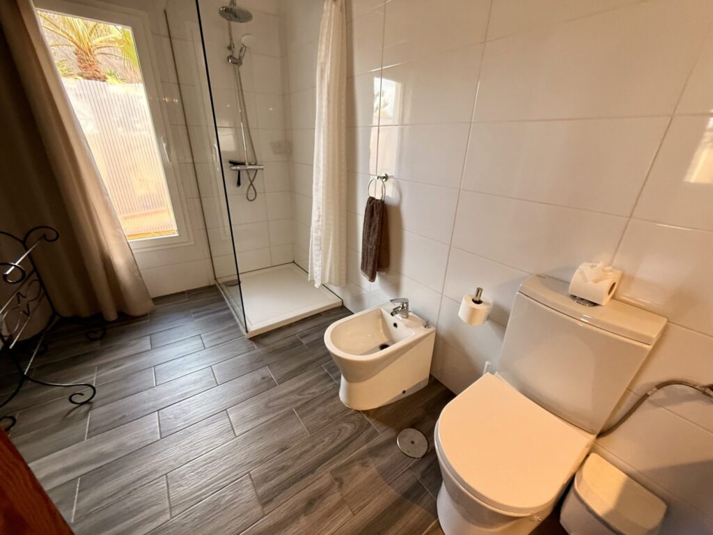 Badezimmer mit Dusche und WC Badezimmer mit Dusche, WC, Bidet und Waschbecken in neutralen Farben.