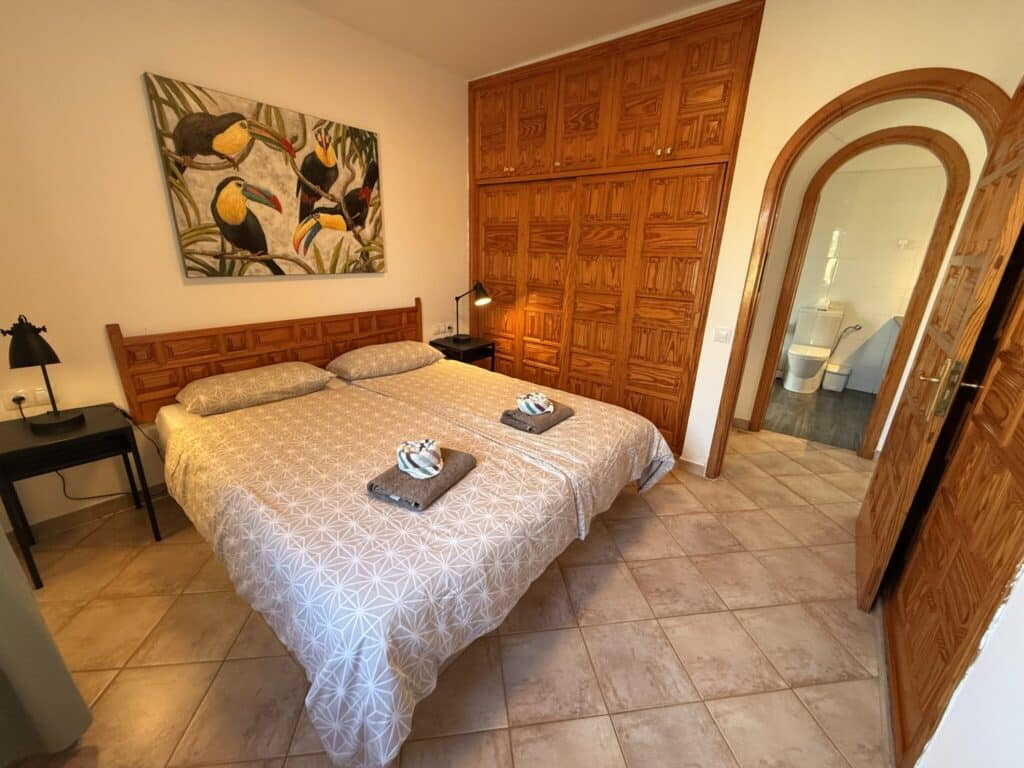 Schlafzimmer mit Doppelbett und Holzschränken Schlafzimmer mit einem Doppelbett, Holzschränken und einem Gemälde an der Wand.