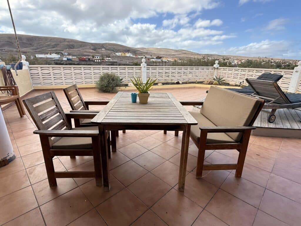 Holztisch mit Stühlen auf einer Terrasse Holztisch mit zwei Stühlen und einem Topf mit Pflanzen auf einer Terrasse.