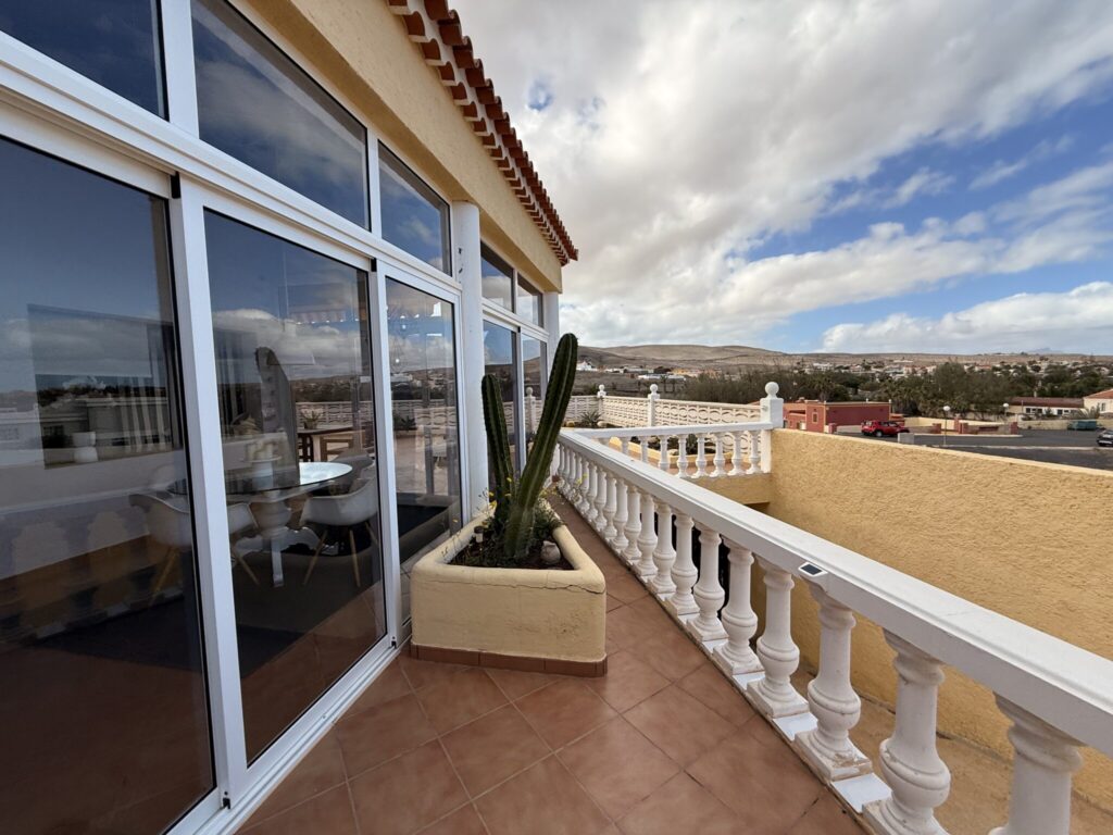 Balkon mit Blick auf die Landschaft in Fuerteventura Balkon mit Glasfront und einem großen Kaktus in einem Blumentopf in Fuerteventura.