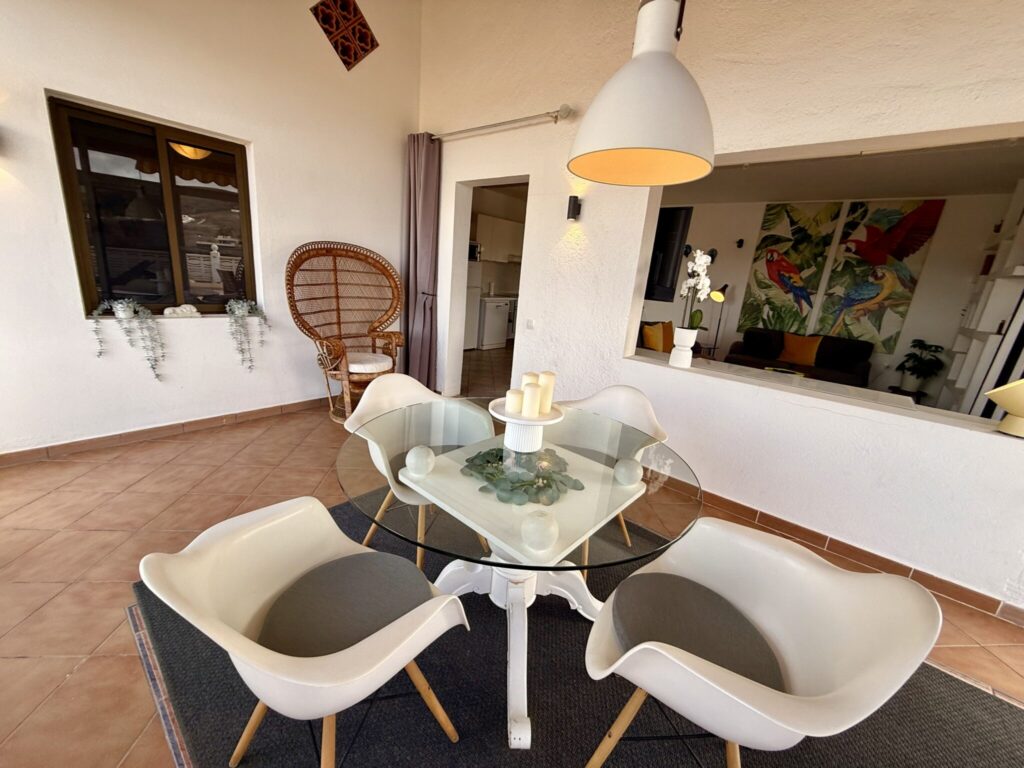 Essbereich mit Glastisch und Stühlen in einer Wohnung Runder Glastisch mit weißen Stühlen in einem modernen Essbereich einer Wohnung.