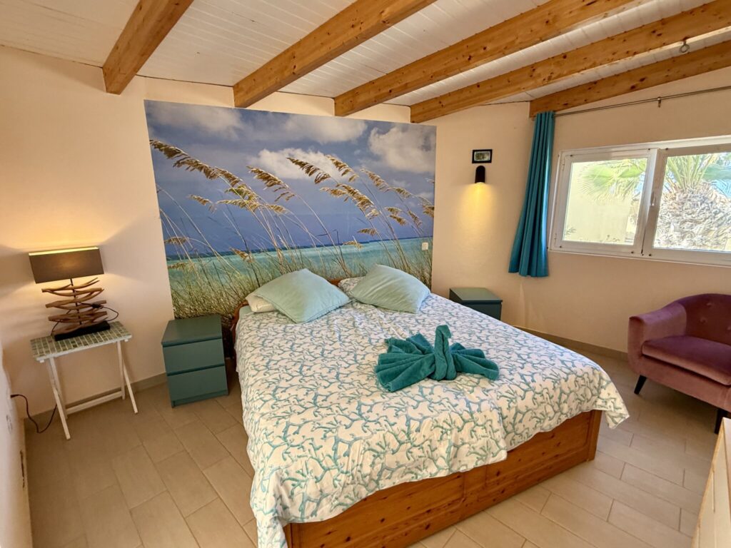 Schlafzimmer mit Bett und Wandbild Schlafzimmer mit einem Doppelbett, dekoriert mit einem Wandbild von Strand und Gras.