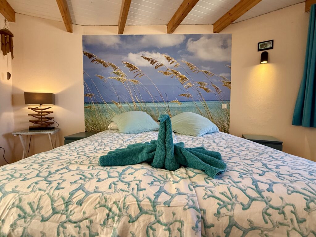 Schlafzimmer mit einem großen Bett und einem Wandbild von Gras und Himmel im Hintergrund.