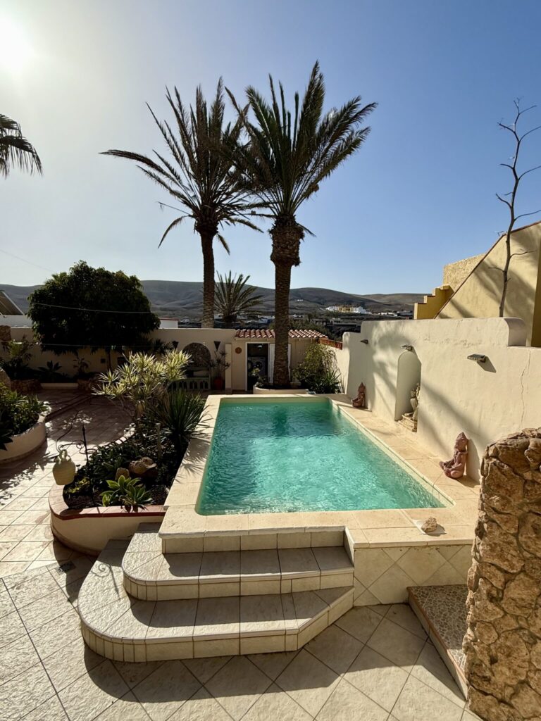 Poolbereich mit Wasser und Palmen in einem Apartment in La Pared, Fuerteventura.