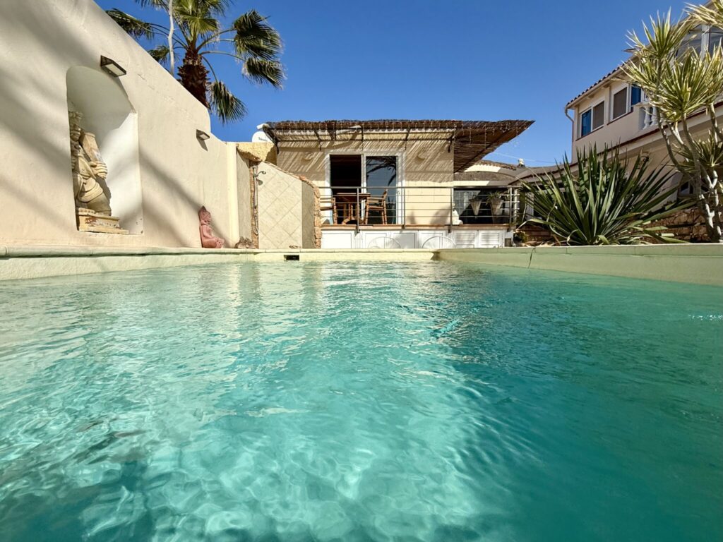 Poolhaus mit klarem Wasser und Pflanzen im Vordergrund in La Pared, Fuerteventura.