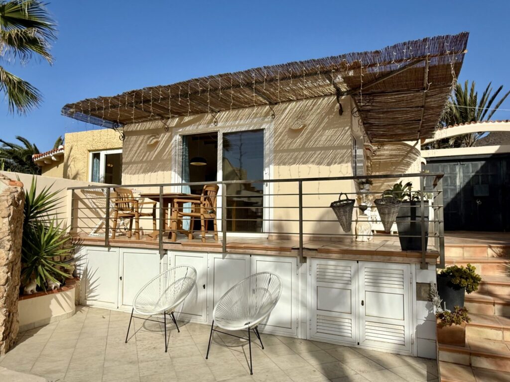 Ein Ferienhaus mit einer Holzterrasse und zwei Stühlen in Fuerteventura.