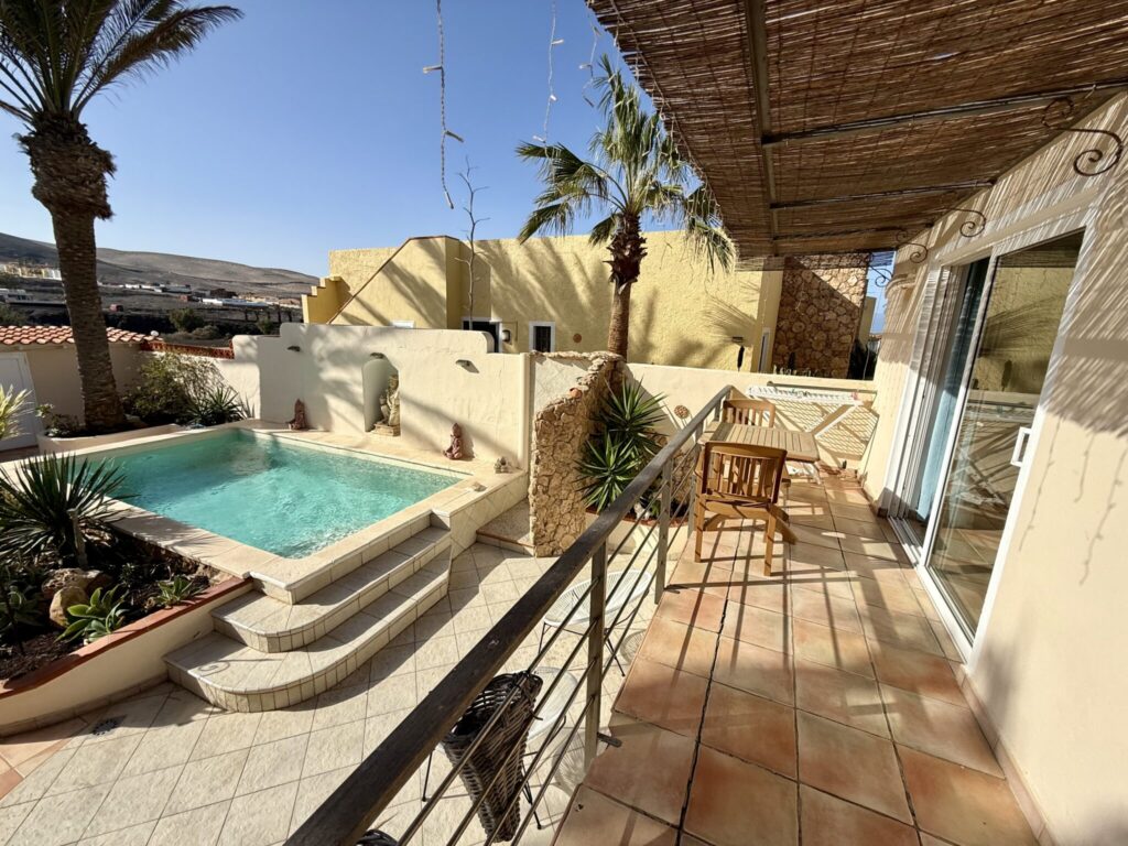 Ein Poolbereich mit einer Terrasse und Pflanzen in einem Surfcamp-Apartment in La Pared, Fuerteventura.
