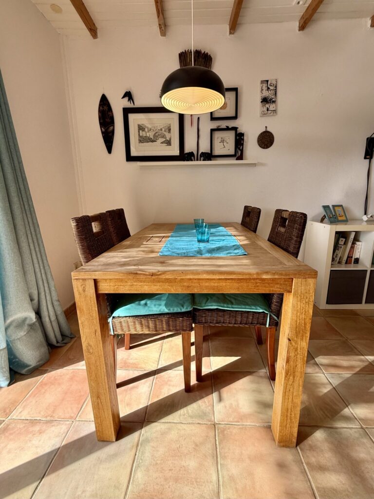 Holztisch mit blauen Tischläufern und Stühlen in einem hellen Innenraum.
