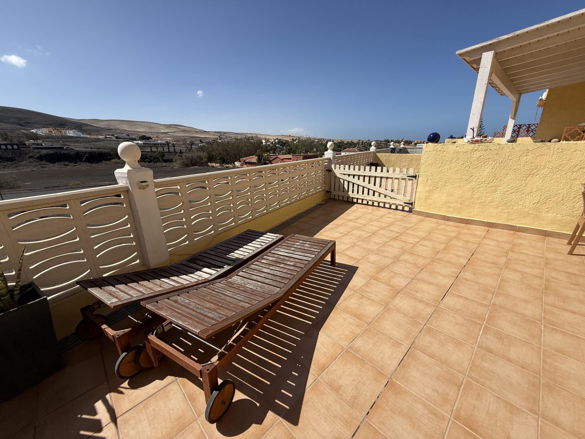 Holzliege auf einer Terrasse in La Pared, Fuerteventura, mit Fliesenboden und Geländer.