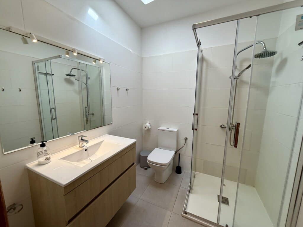 Modernes Badezimmer mit Dusche, Waschbecken und Spiegel in neutralen Farben.