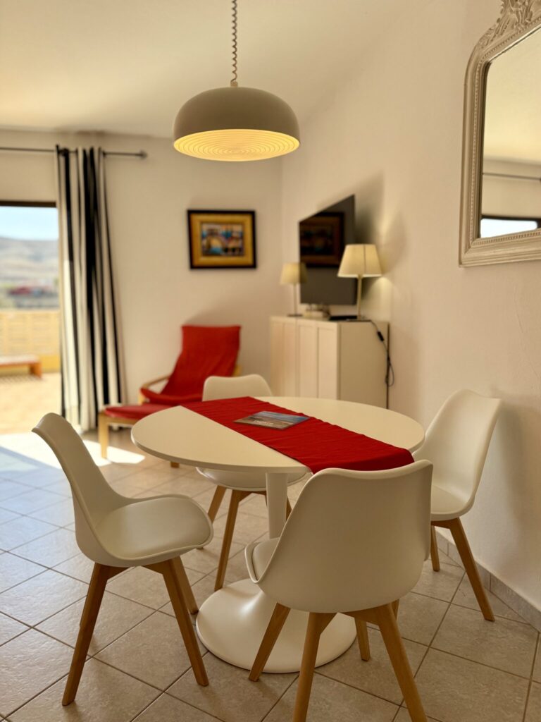 Essbereich mit runder Tisch und Stühlen Ein runder Tisch mit weißen Stühlen und einer roten Tischdecke in einem hellen Raum.