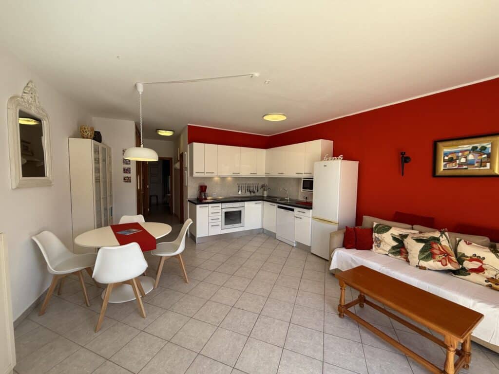 Küche und Wohnbereich eines Apartments mit roter Wand und Essbereich.