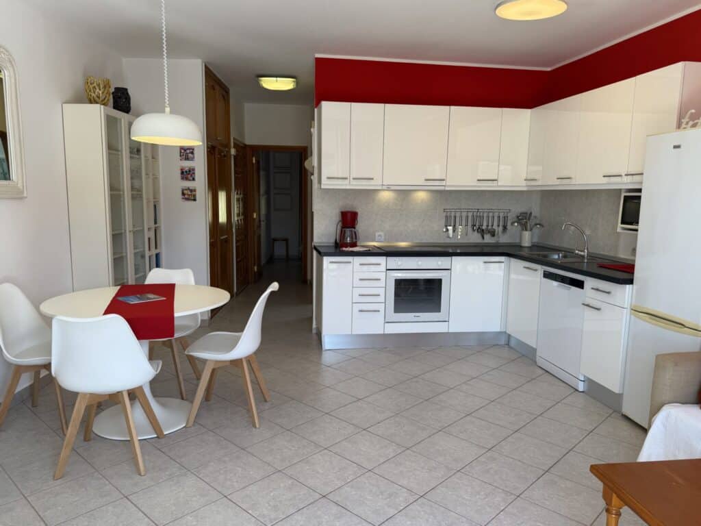 Moderne Küche mit weißen Schränken, einem Tisch und Stühlen in einem Apartment.